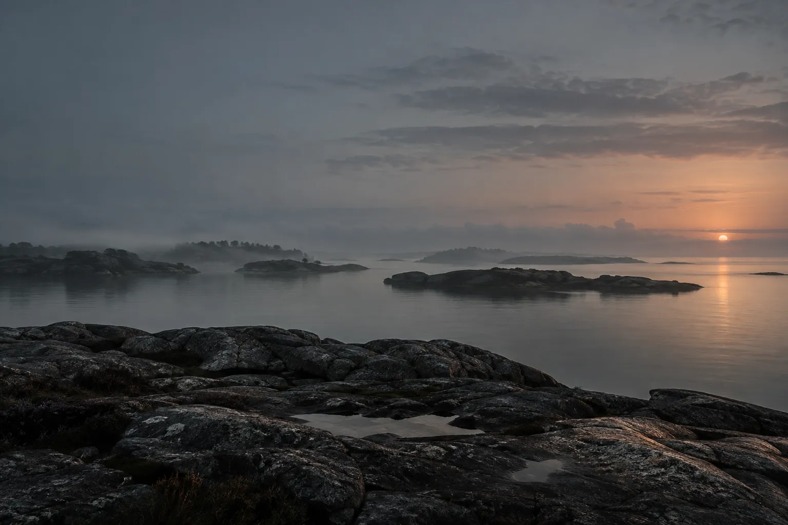 Nordic granite shoreline at grey dawn, still water and islands receding into fog.